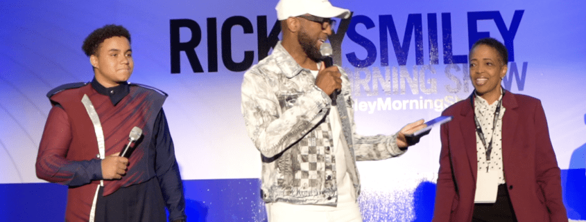 Three people speaking on stage with microphones.